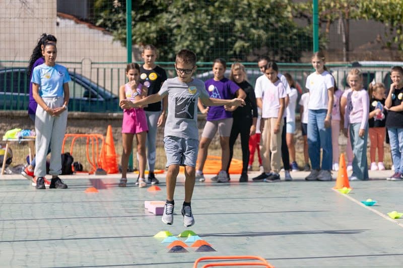 Деца на спортната площадка между конусите по време на занимание